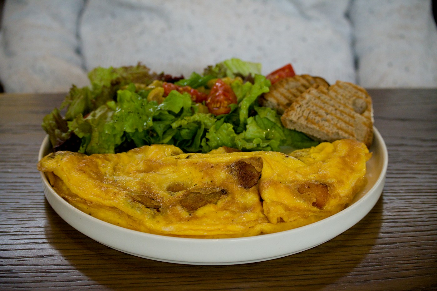 Omelete servida num prato com salada e pão